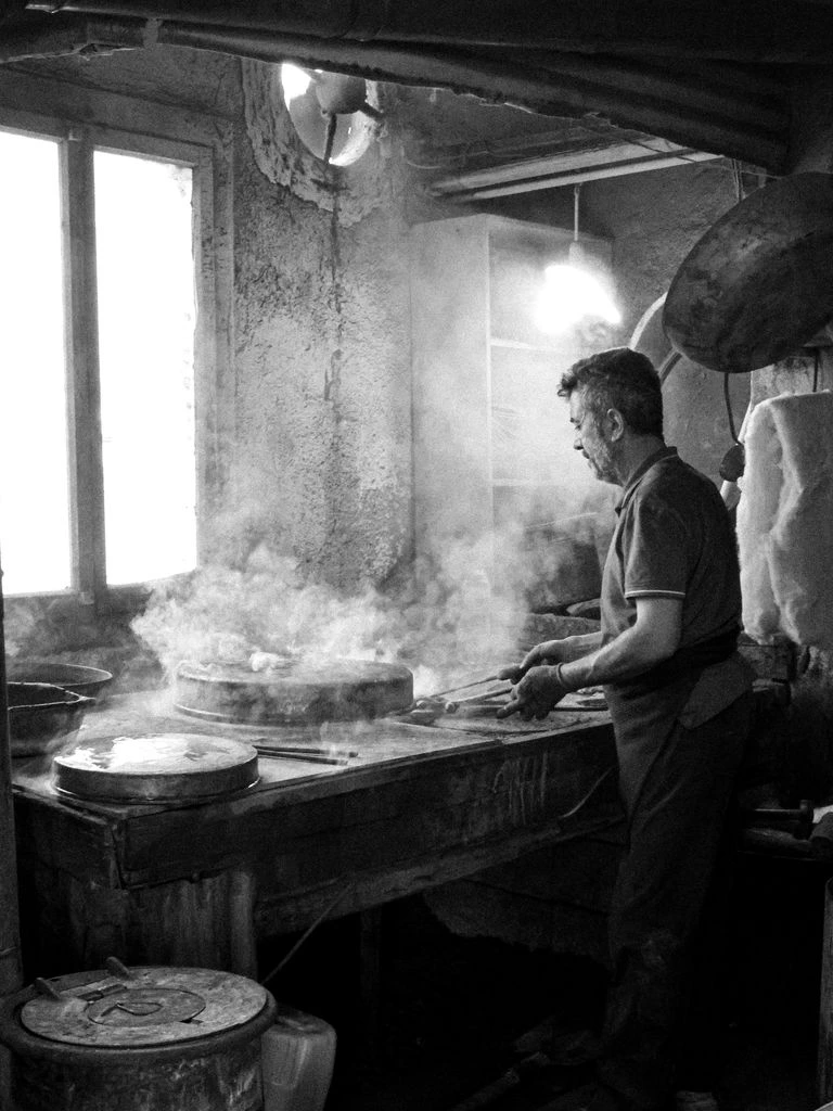Un casaro mastro incide il marchio a fuoco su una forma di Parmigiano Reggiano nella lavorazione del mattino