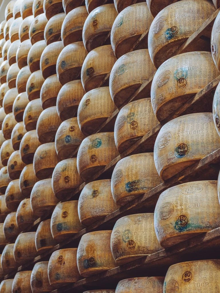 Quarto di forma di Parmigiano Reggiano DOP su carta paglia, coltello a lama lunga